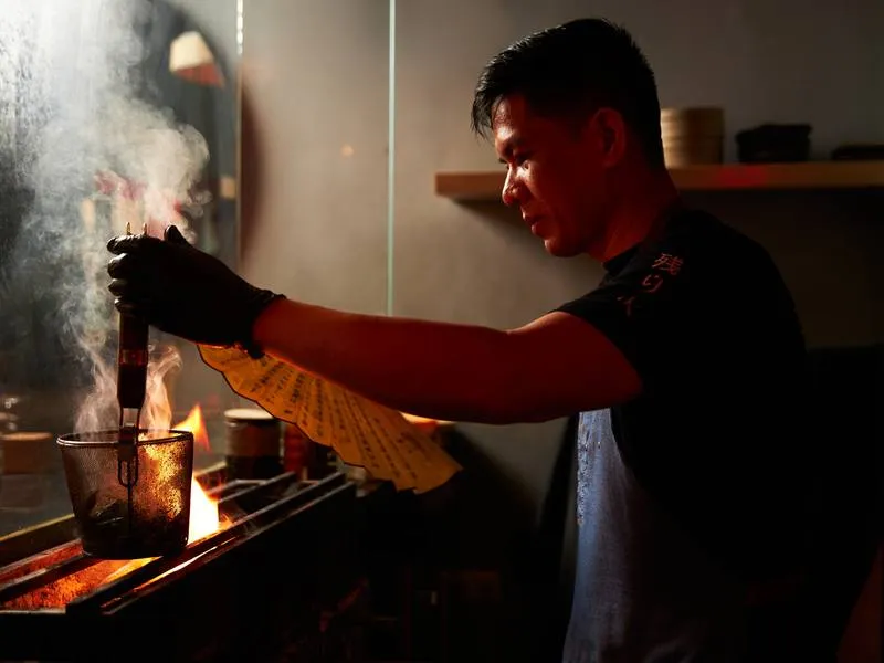 Cocinero avivando la brasa de carbón en el puesto de Ichiba